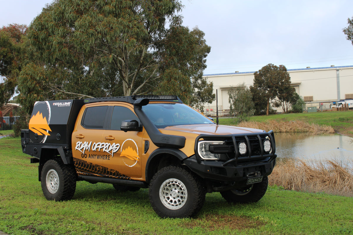 The Roam Offroad ute with a bull bar, tray and canopy, parked on the grass by the water
