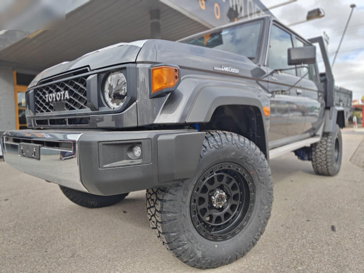 Front of the grey LandCruiser 79 Series on black wheels and all-terrain tyres