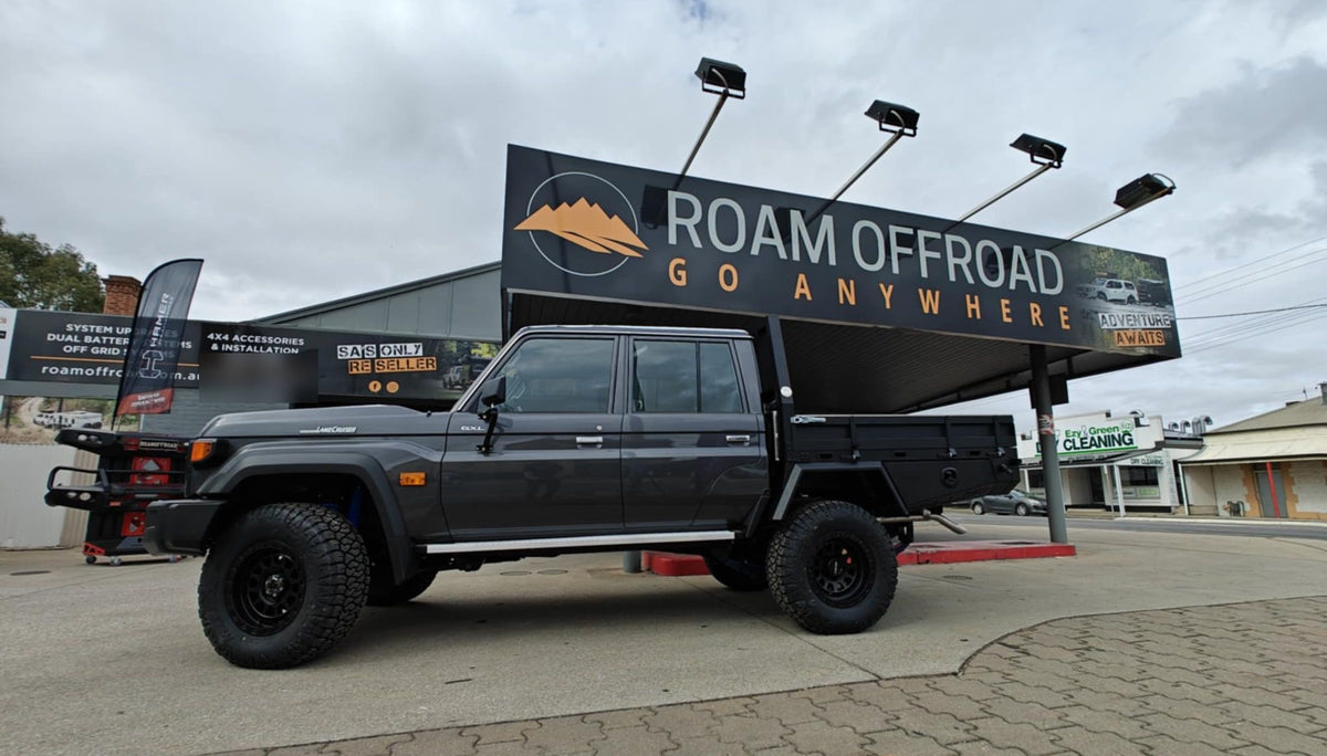 Grey LandCruiser 79 Series dual cab with an XGO tray, parked under the Roam Offroad sign