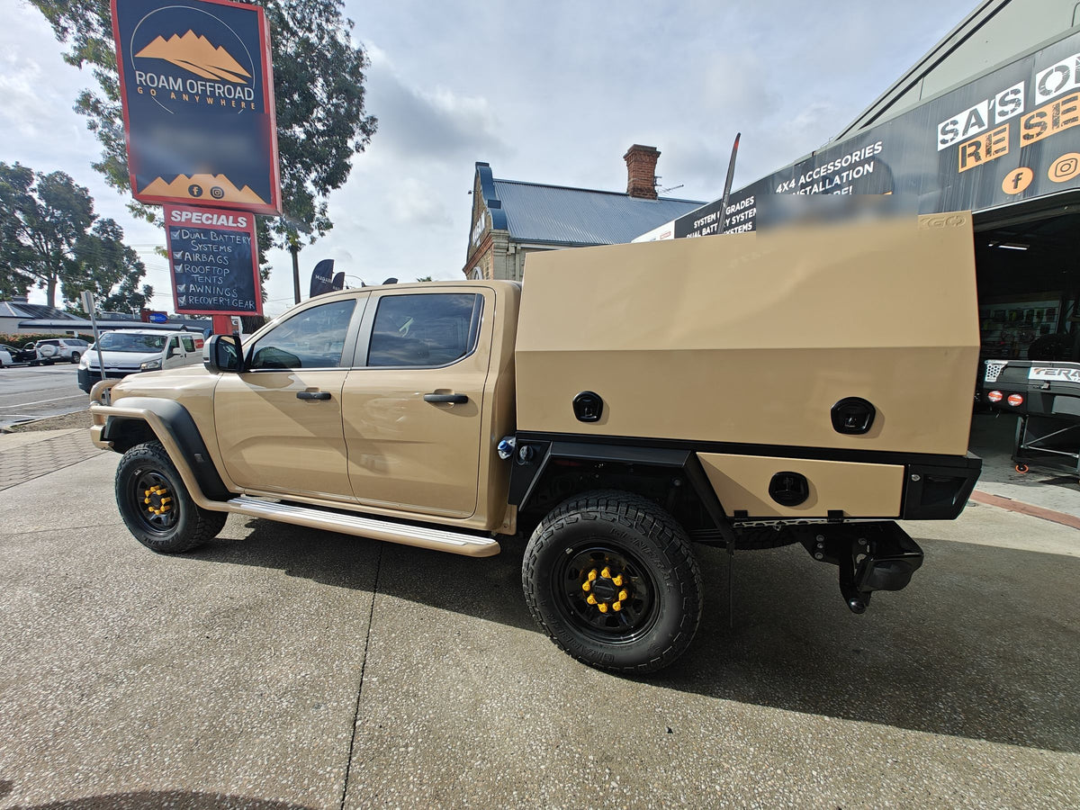 Tan dual-cab ute with a colour-matched canopy and black tray outside the Roam Offroad shop